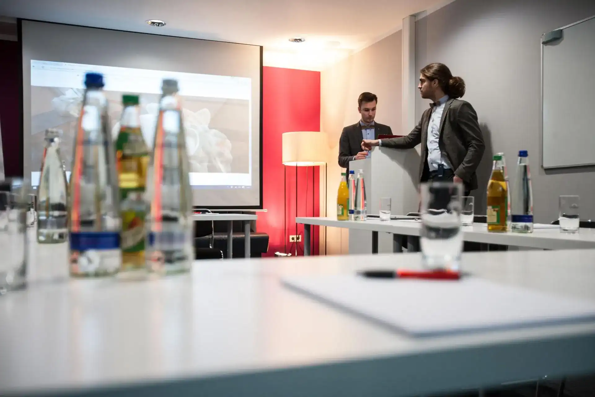 Tagungsraum mit Leinwand, Getränken und Präsentation