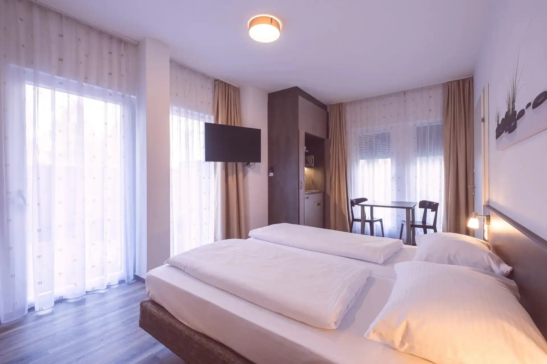 Komfortzimmer mit Doppelbett, bodentiefen Fenstern, Kitchenette und Essplatz