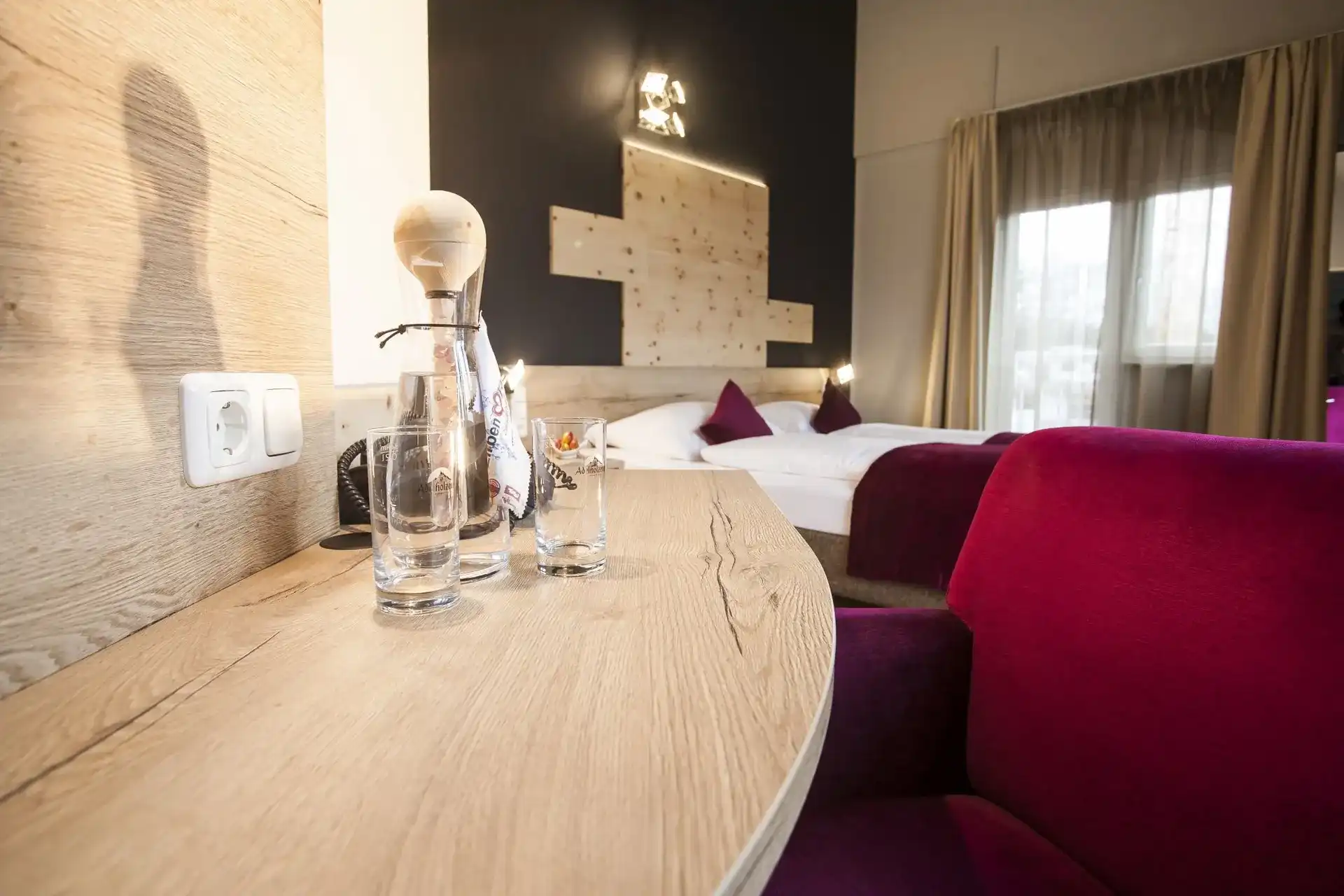 Schreibtisch mit Karaffe und Gläsern, im Hintergrund das Bett